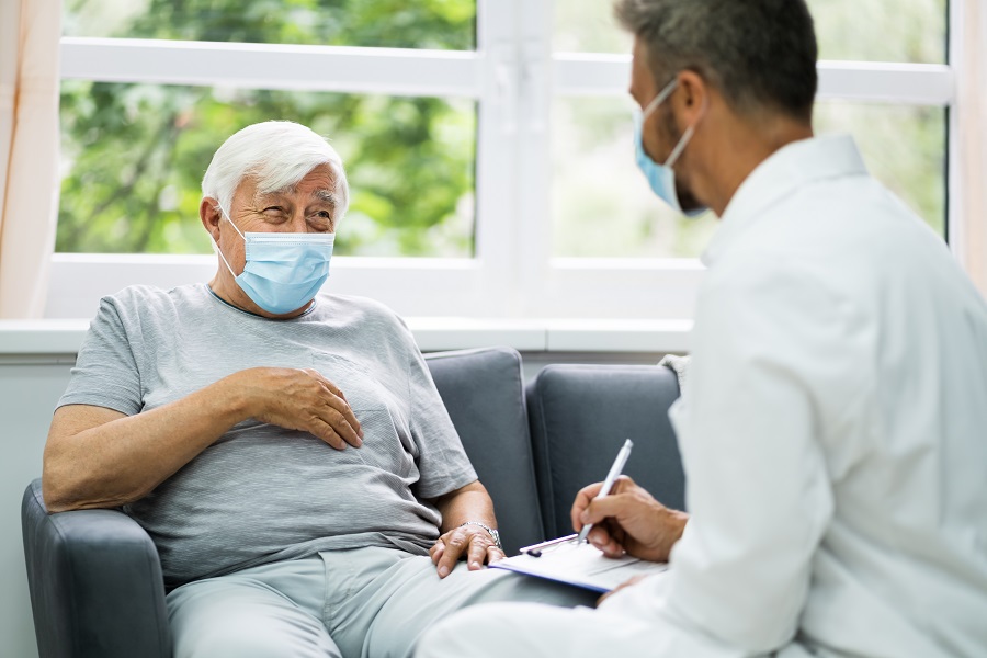 Patient mit Maske im Gespräch mit Arzt
