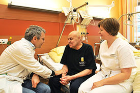 Prof. Christoph Ostgathe im Gespräch mit einem Patienten und eine Pflegerin