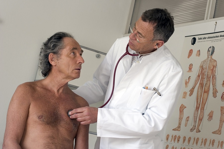 Ein Arzt hört das Herz eines Patienten mit einem Stethoskop ab.