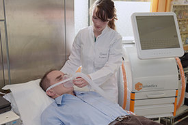 Patient atmet mit Unterstützung durch eine medizinische Fachangestellt in eine Atemmaske. 
