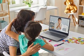 Mutter und Kind vor Laptop beraten sich mit Ärztin